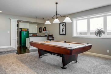 Bright daylight basement with pool table and overhead lighting