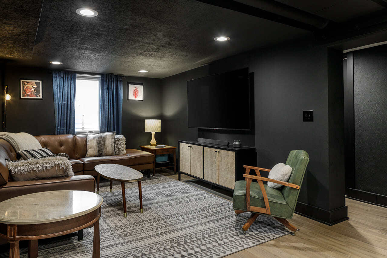 Sitting area in a basement with carpet flooring and black-painted walls