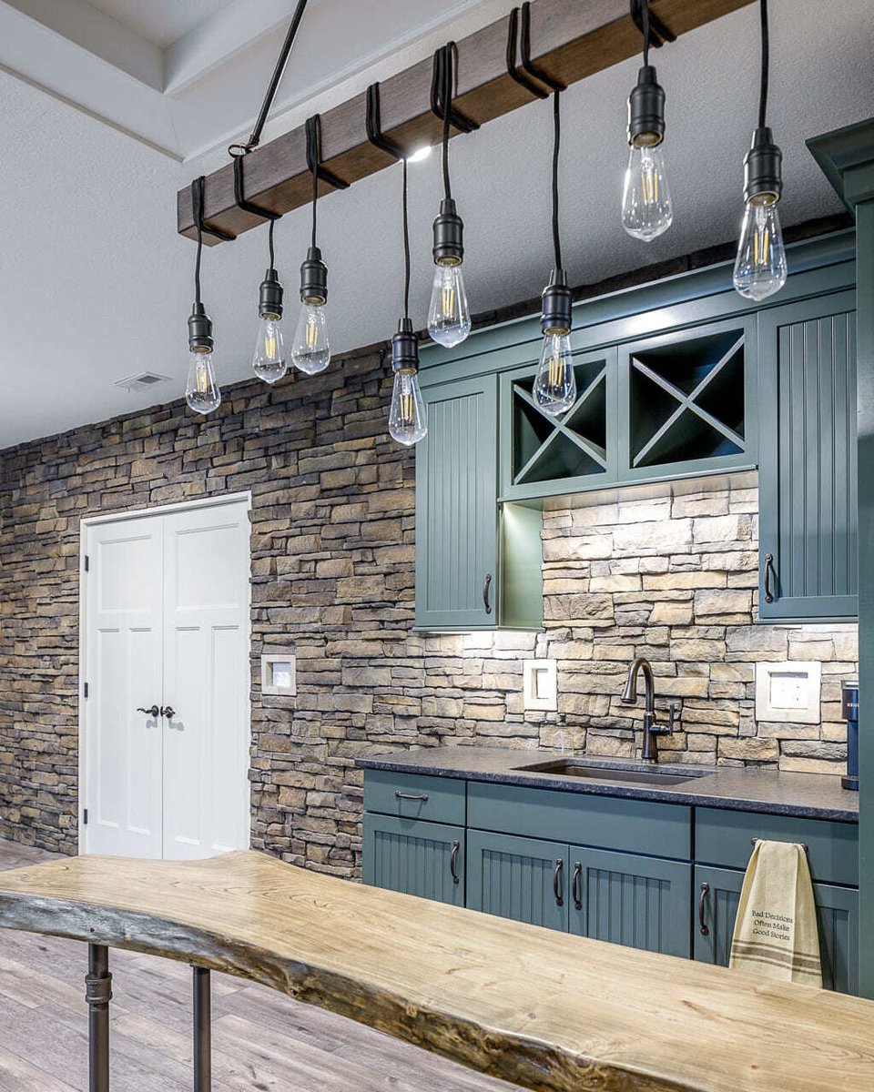 wired light fixtures curled over a wood beam overlooking a hardwood table, washing sink and cupboard in a basement bar