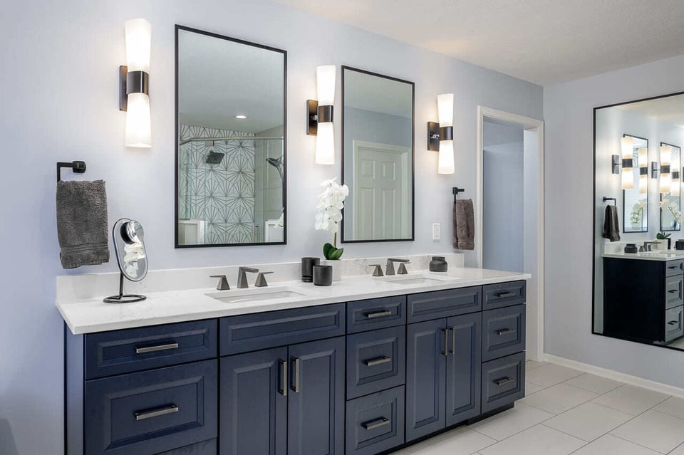 A bathroom with tapered wall sconces and square wall mirrors