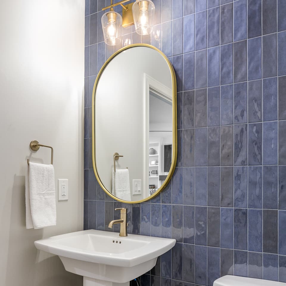 A bathroom sink without vanity. A mirror fixed to the wall and light fixture overhead