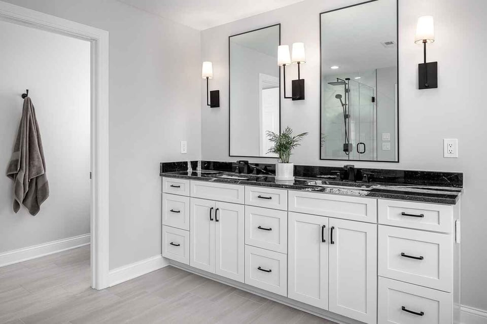 A sleek white and color themed bathroom with marble countertop vanity and a square mirror fixed to the wall