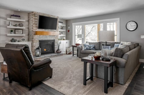 Whole Home Remodel Living Room with Stone Fireplace Floating Shelves Oversized Windows and Custom TV Built-Ins | Compelling Homes