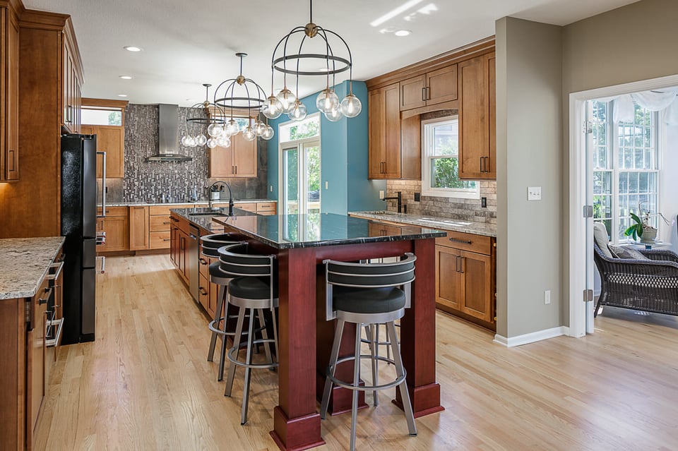 Warm-themed kitchen with high sitting stools and black countertops