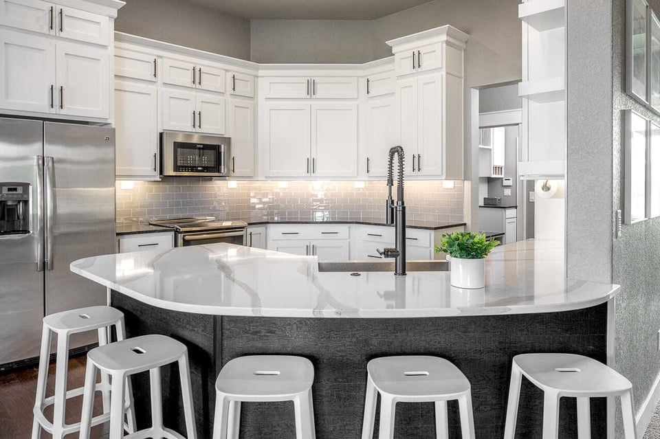 Small kitchen space fitted with white cabinet, countertops and stools