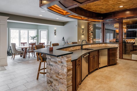 Custom Bar with Wine Cellar and Kitchen Area Overlooking Dining Room with Natural Light in Walk Out Basement | Compelling Homes Des Moines, IA