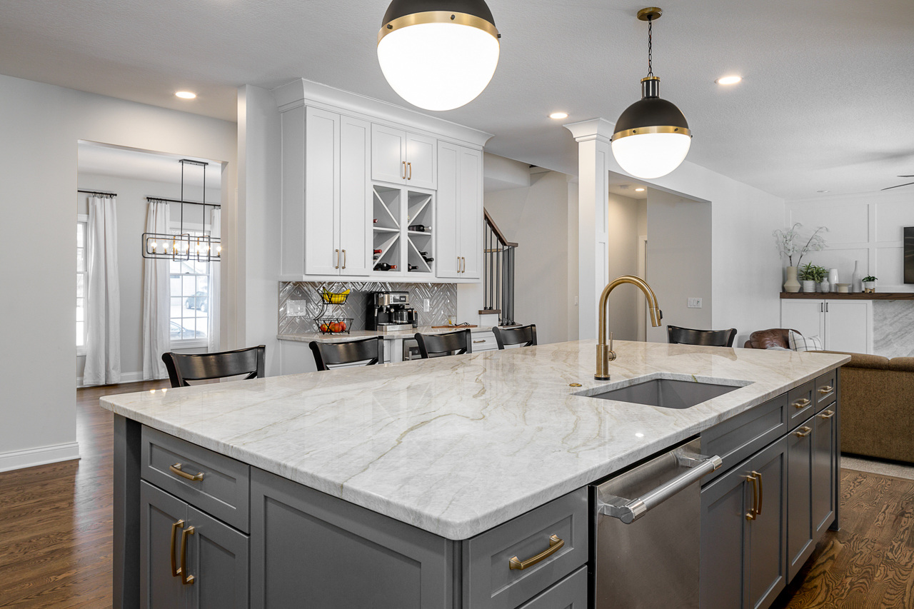 Full Kitchen Showcasing a Marble Countertop, Cabinets and Light Fixtures