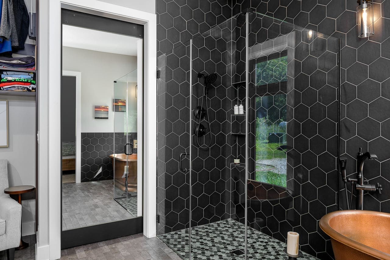 Black Tile Shower Walls with Large Free Standing Brass Bathtub | Compelling Homes