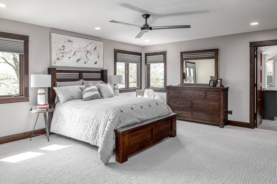 A bedroom fitted with white carpet and wooden cupboards