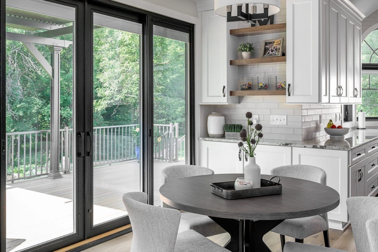 White Kitchen with Black Sliding Door to Deck and Floating Shelves Over White Glass Subway Tile | Compelling Homes Design Build